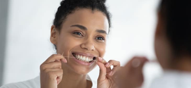 Woman flossing in mirror