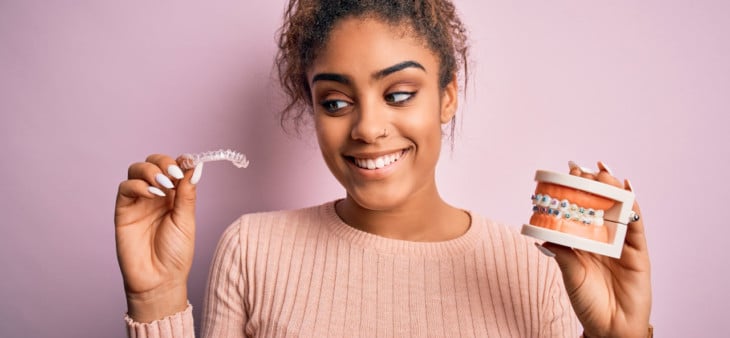 Woman holding up clear aligner braces