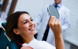 Woman holding dental mirror in chair
