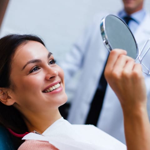 Woman holding dental mirror in chair