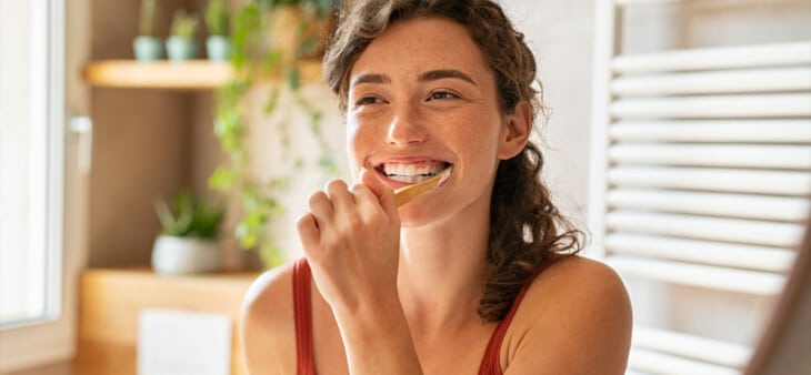 Woman brushing teeth in mirror