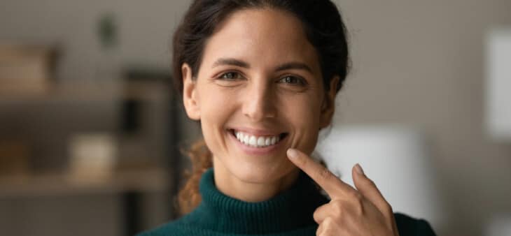Woman smiling and pointing to her teeth
