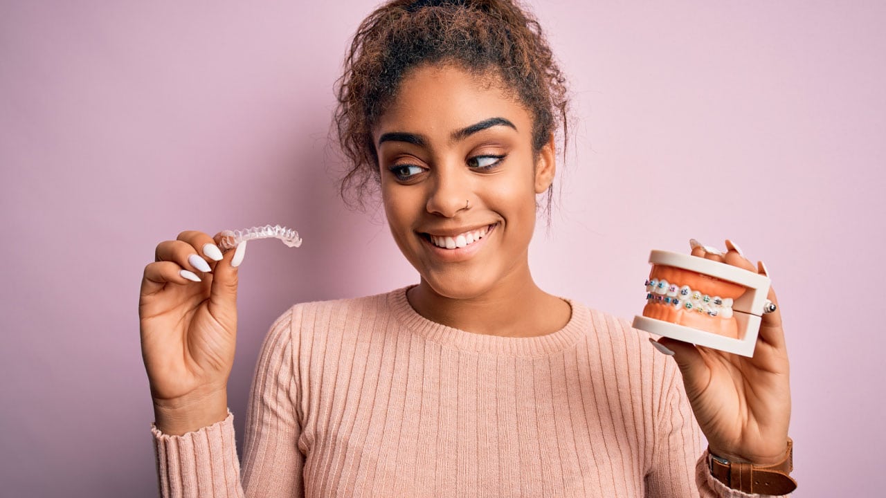 Woman holding up clear aligner braces