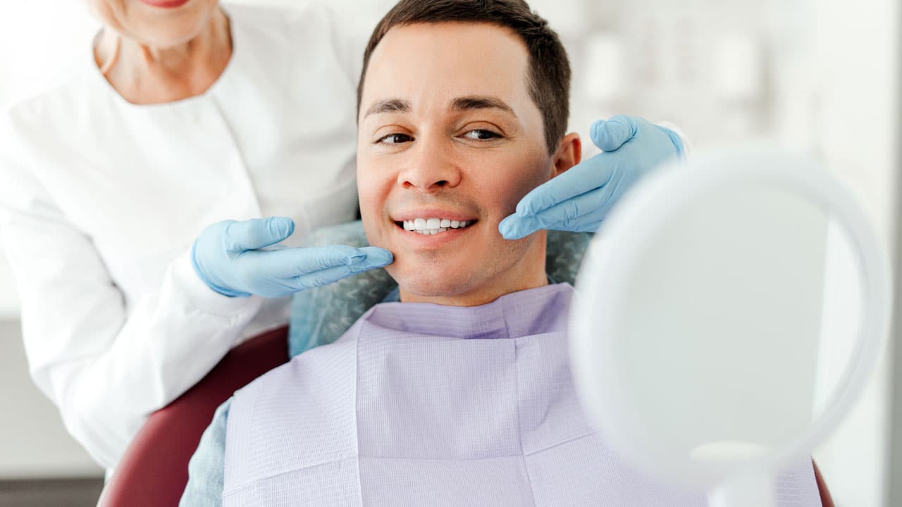 Man sitting in dental chair admiring smile